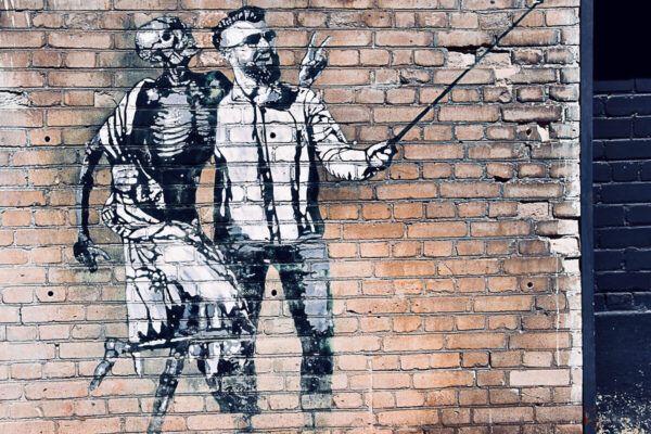 Tallinn Sehenswürdigkeiten: Mural an Backsteinmauer, das einen Mann mit Selfiestick und ein Skelett zeigt