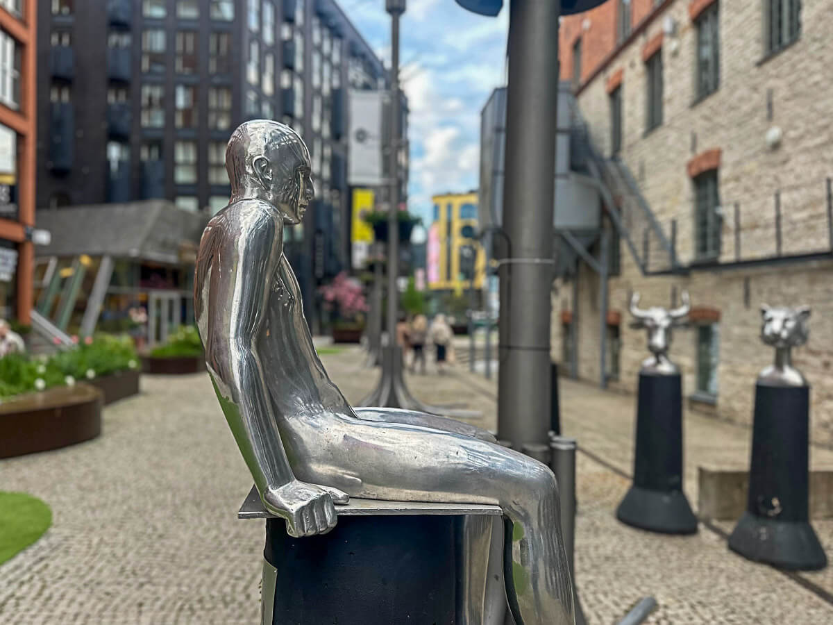 Skulptur eines Mannes in Silber vor Stadtkulisse